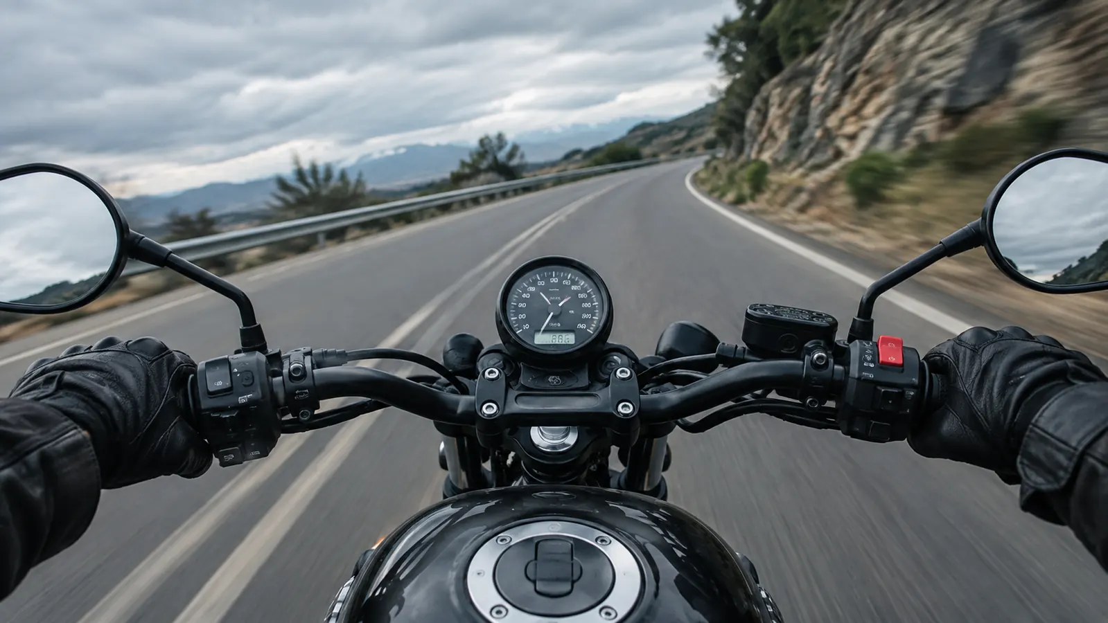 A rider's hands in leather gloves gripping the handlebars on a winding road